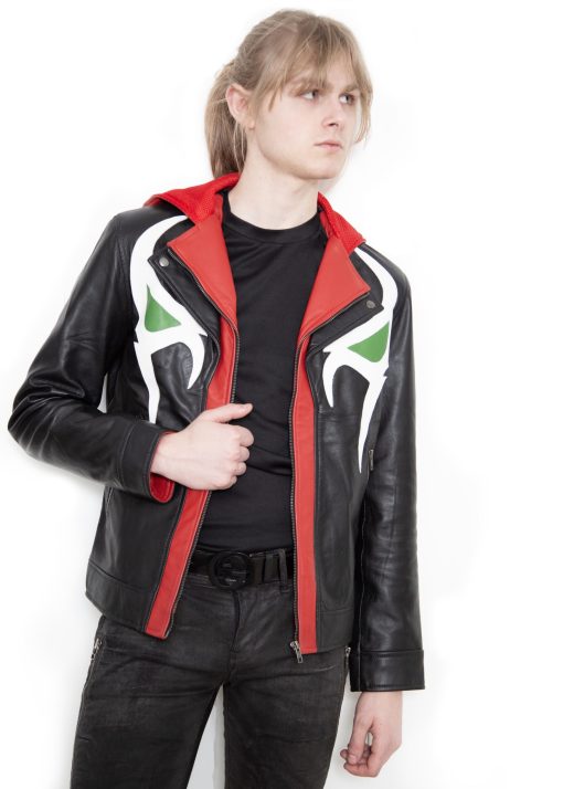 (Front): Photo of a model wearing a black leather jacket. The jacket is a motorcycle cut with a red hood and a red leather lining that is visible inside the cuffs and the folded down collar. There is also a strip of red leather either side of the front zipper. Where breast pockets typically would be on a jacket, there are [handpainted/patched] green eyes surrounded by white details. The collar has metal pop buttons to hold it in place. (Back): Photo of the same black leather jacket with a red hood. The jacket is a motorcycle cut. The inside of the hood has a mesh lining.