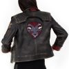 Photo of a model wearing a dark brown leather jacket. The back of the jacket is visible, showing the same 3/4 length red studded leather cuffs and the light brown X on the left upper arm. The back of the jacket has a large patch, showing a two-headed dog wearing a studded collar, both heads with their mouths open and teeth bared. The background of the patch is in the shape of an upside-down teardrop.The jacket pictured is the Vi arcane season 2 jacket.